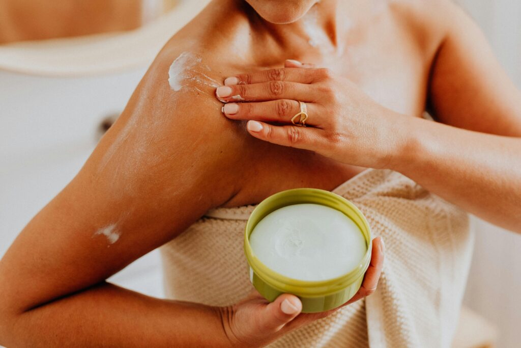 Close-up of a woman applying cream to her shoulder, focusing on skincare and self-care routines.